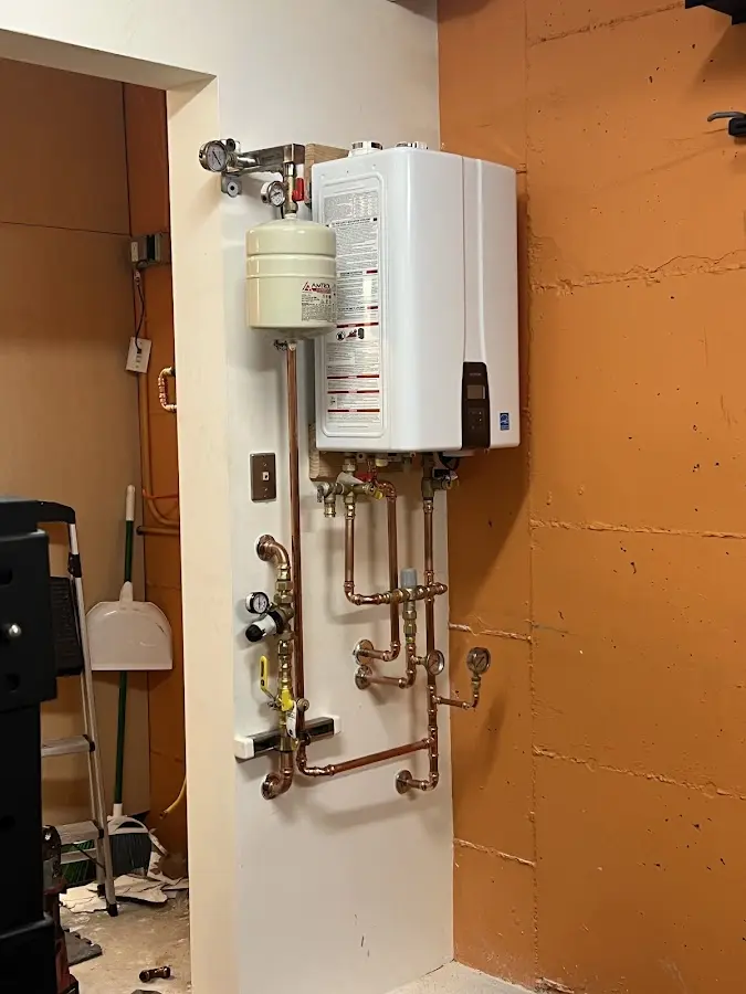 Plumbing technician inspecting water heater connections in Vernon